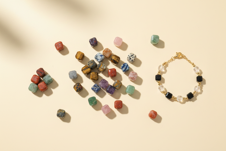 Colorful faceted cube gemstone beads arranged beside a minimalist bracelet in an overhead jewelry-making scene