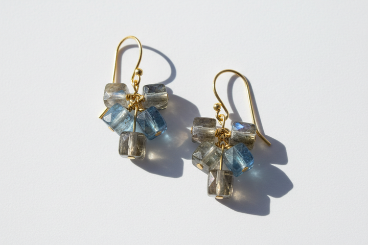 Handmade beaded earrings with pale blue and clear gemstone cube beads hanging from gold ear wires