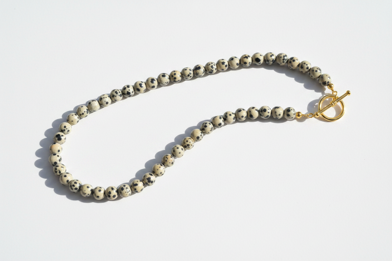 Finished gemstone bead necklace of black-spotted dalmatian jasper rounds fastened with a gold toggle clasp