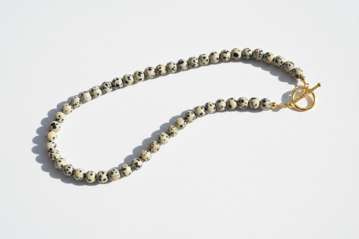 Finished gemstone bead necklace of black-spotted dalmatian jasper rounds fastened with a gold toggle clasp