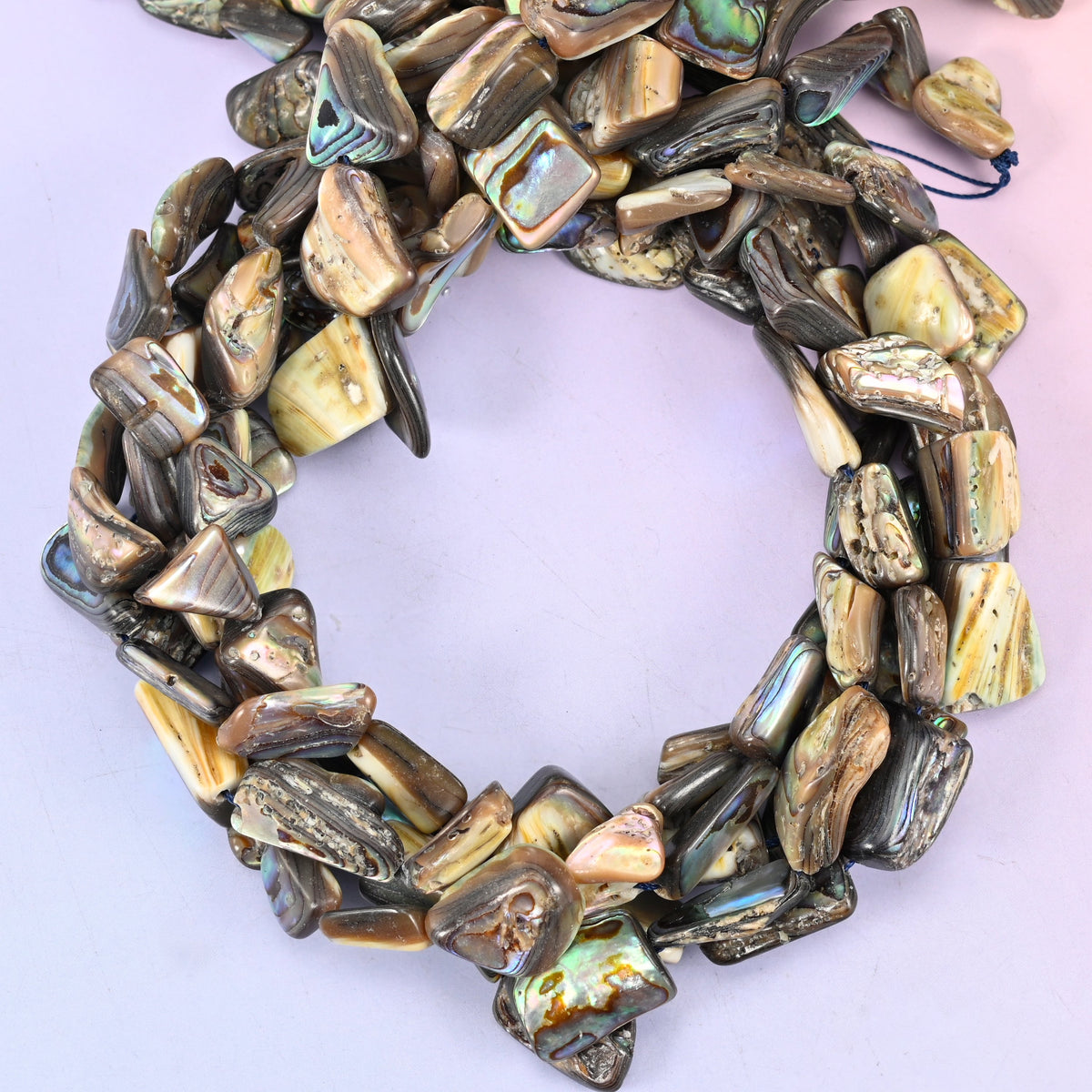 Abalone shell freeform bead strands coiled, showing the larger one-side-polished pieces