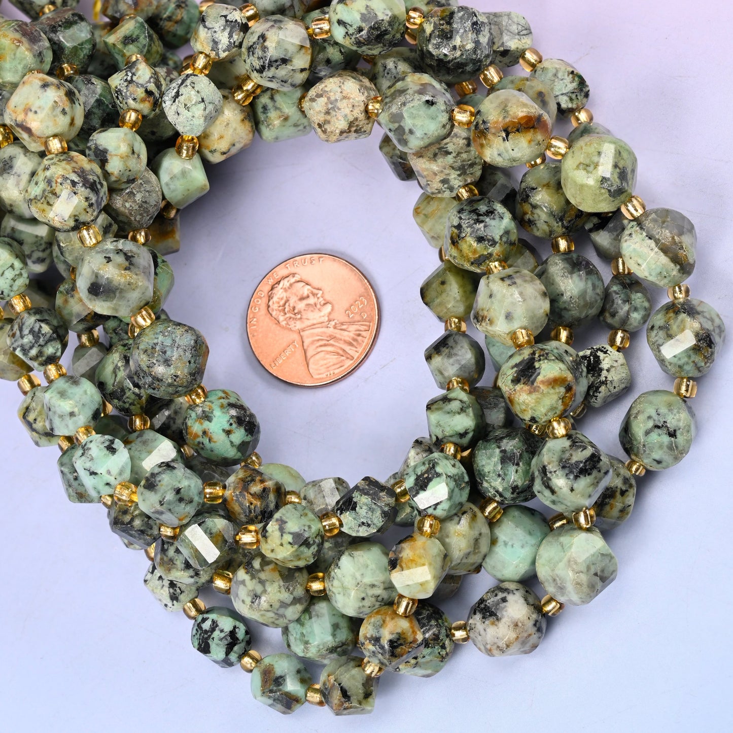 African Howlite faceted spiral twist bead strands coiled around a US penny for size reference