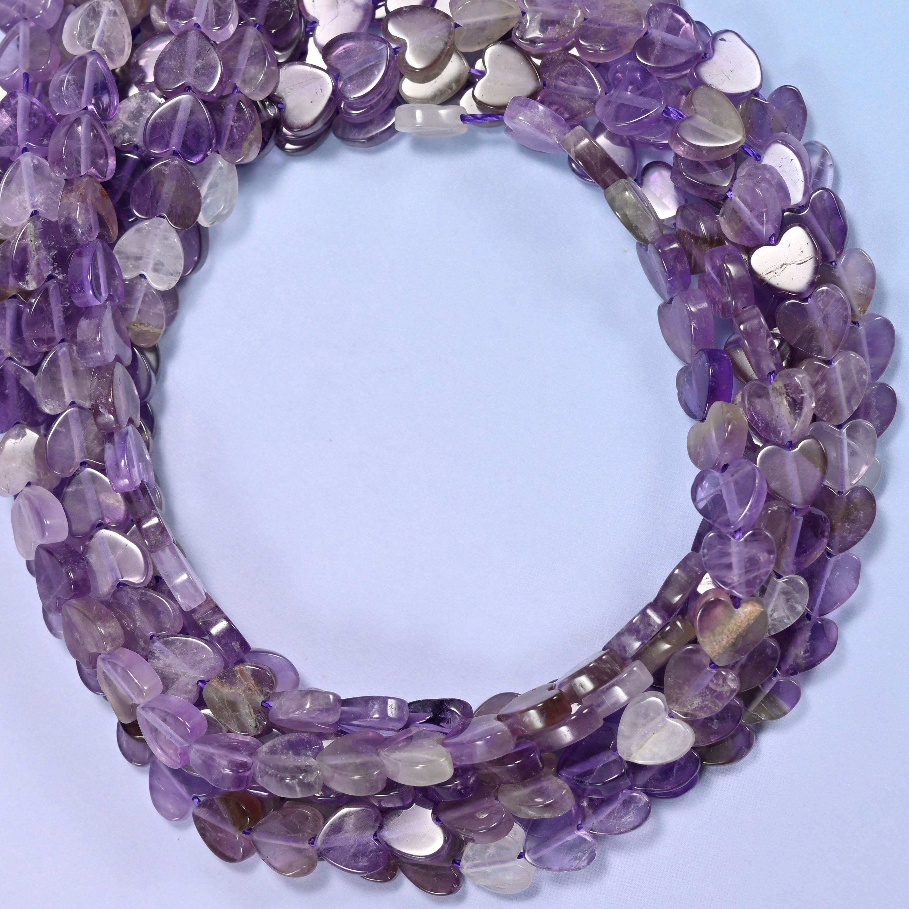 Amethyst flat heart beads, close view of the coiled strands in purple shading into grey and clear
