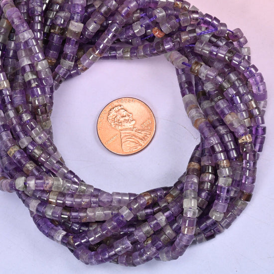 Amethyst smooth heishi disc bead strands coiled around a US penny for size reference