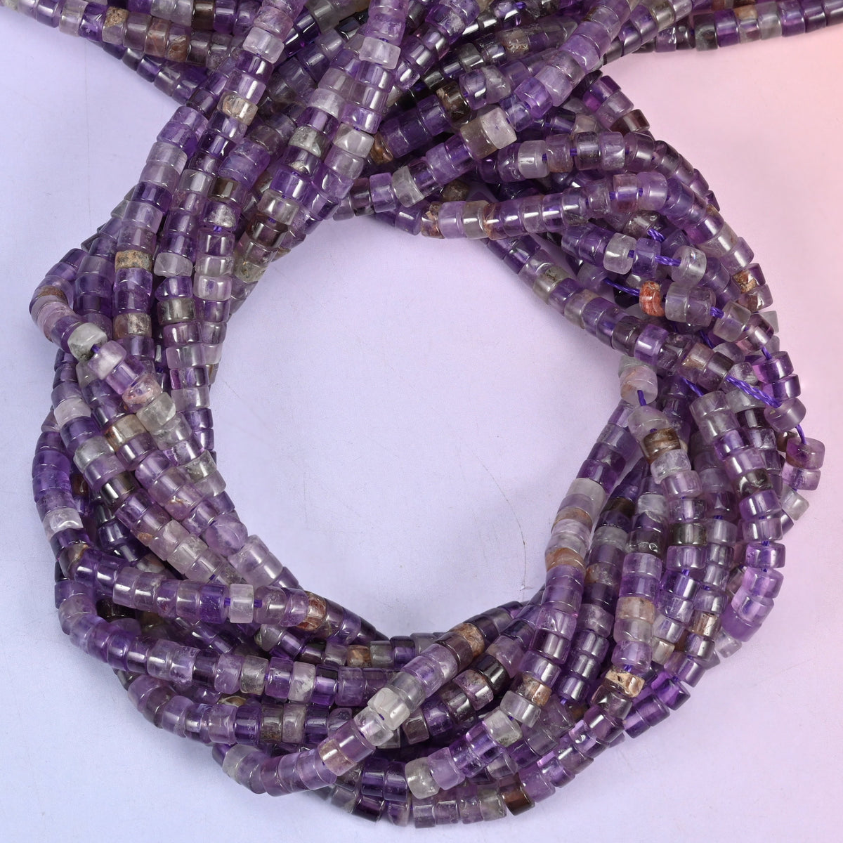 Amethyst smooth heishi disc beads, close view of the coiled strands showing purple with lighter grey-white bands