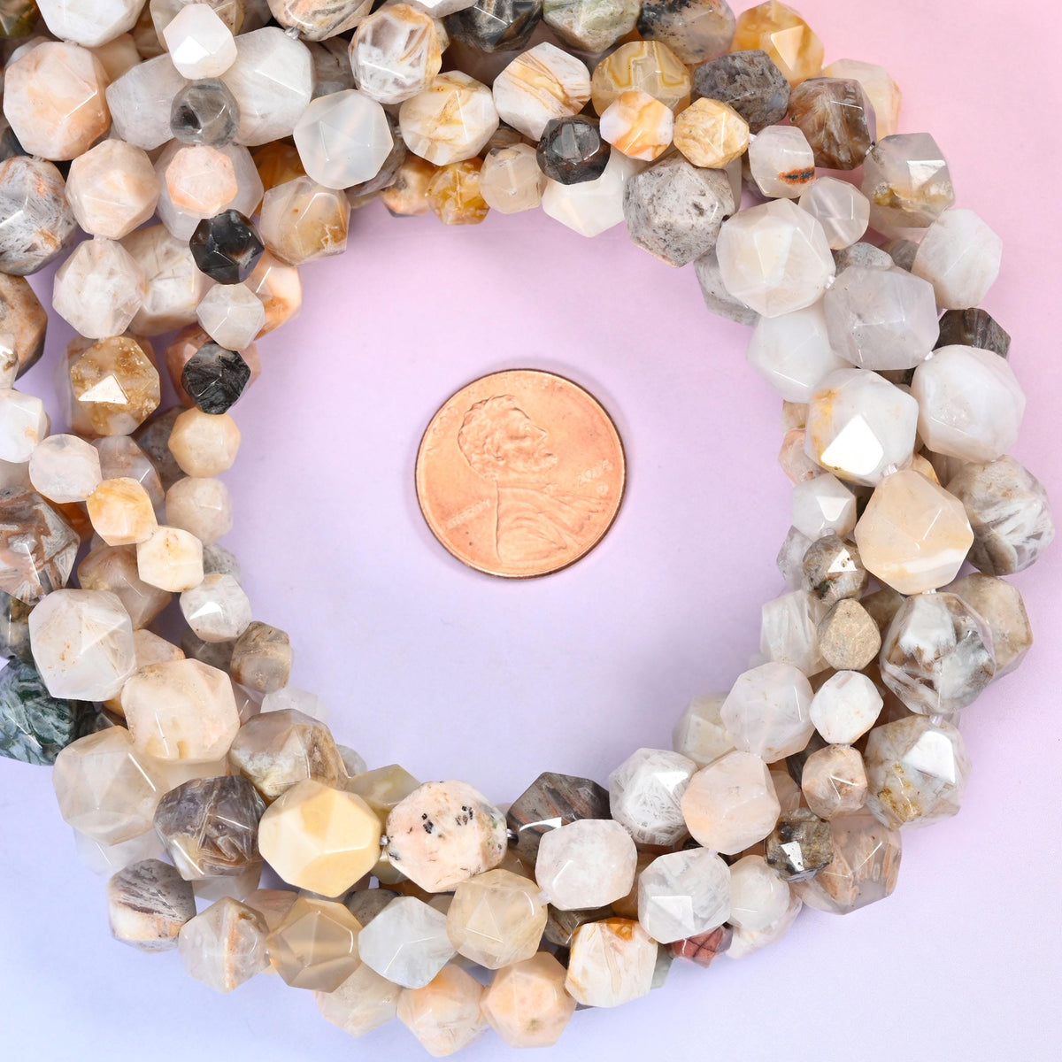 Bamboo agate faceted diamond star cut bead strands coiled around a US penny for size reference