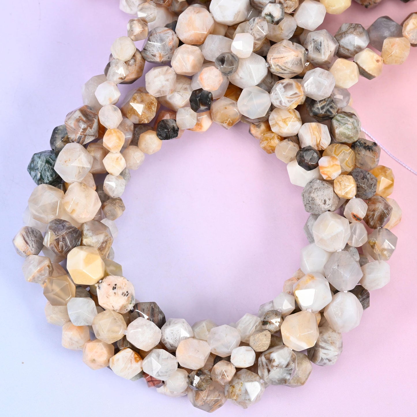 Bamboo agate faceted diamond star cut beads, strands coiled into a ring showing the cream, grey and pale gold banding