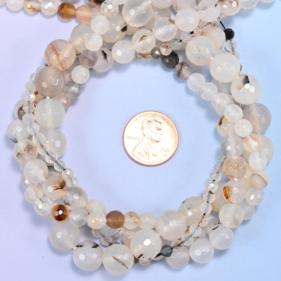 Black Flower Agate faceted round bead strands coiled around a US penny for size reference