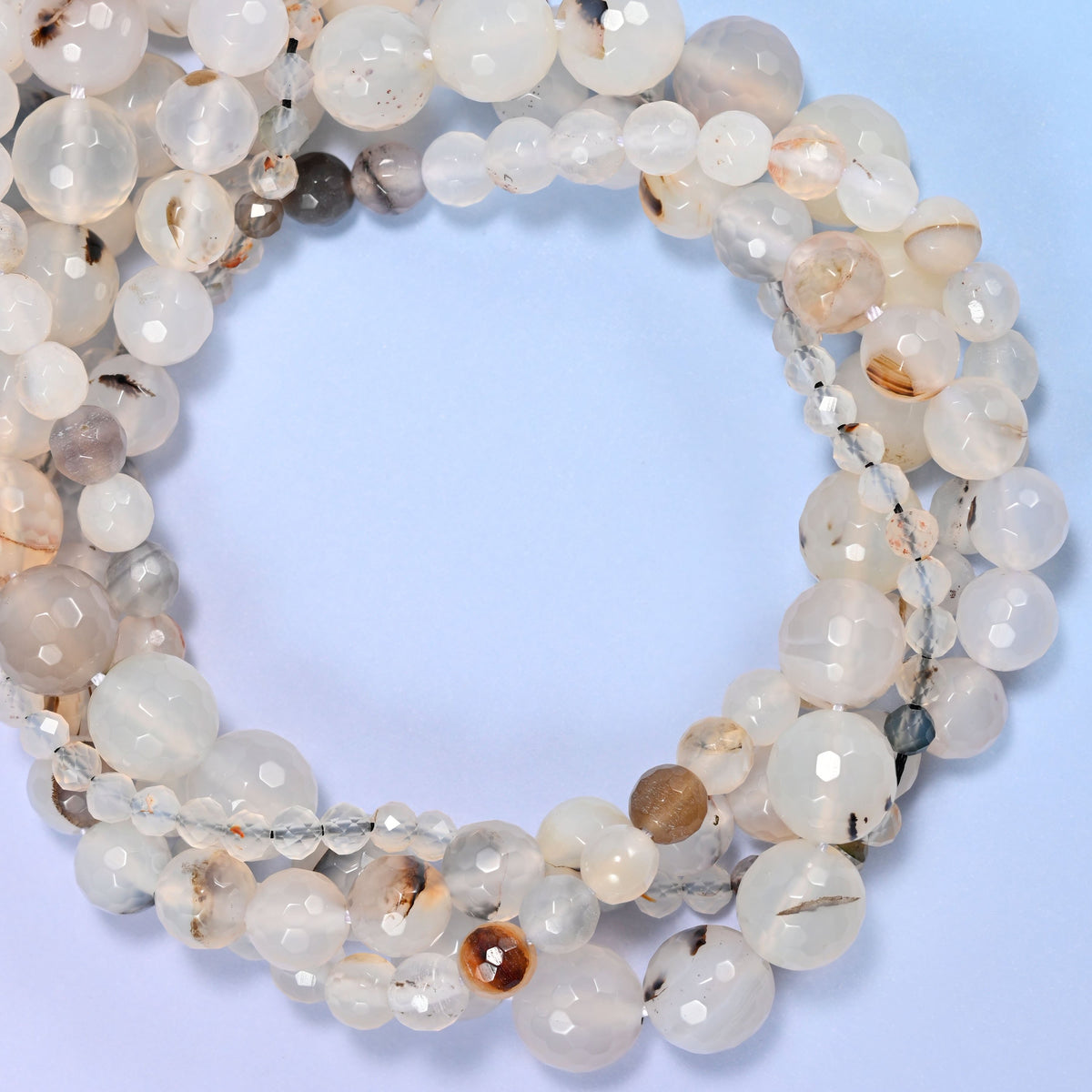 Black Flower Agate faceted round beads, close view of the coiled strands showing milky white with dark flecks