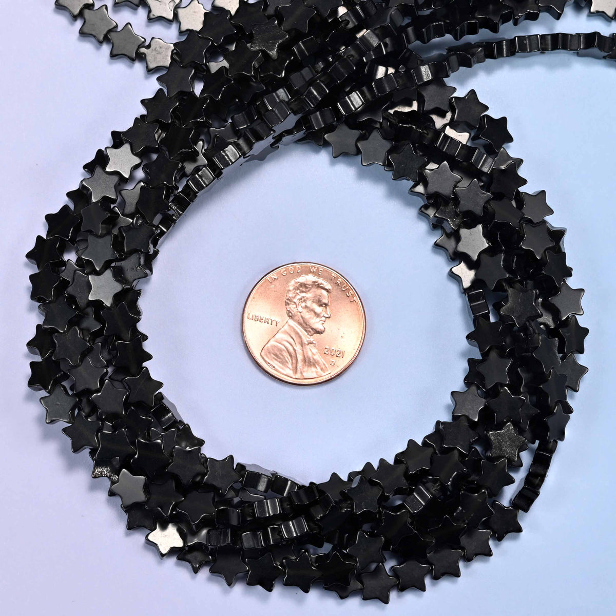 Black Obsidian flat star bead strands coiled around a US penny for size reference