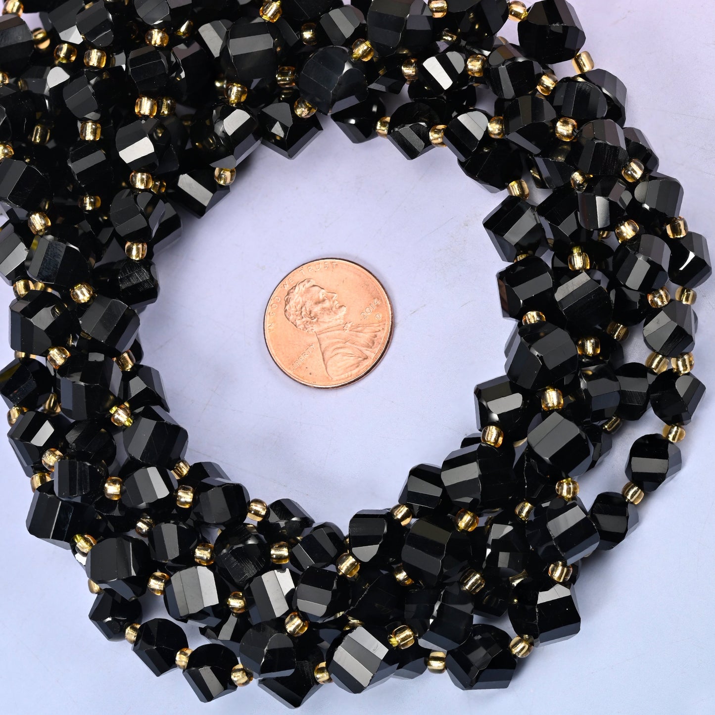 Black Onyx faceted spiral twist bead strands coiled around a US penny for size reference