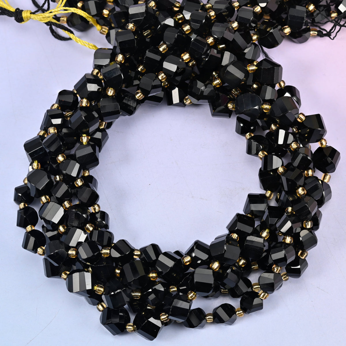 Black Onyx faceted spiral twist beads, close view of the coiled strands in glossy black with gold spacer beads