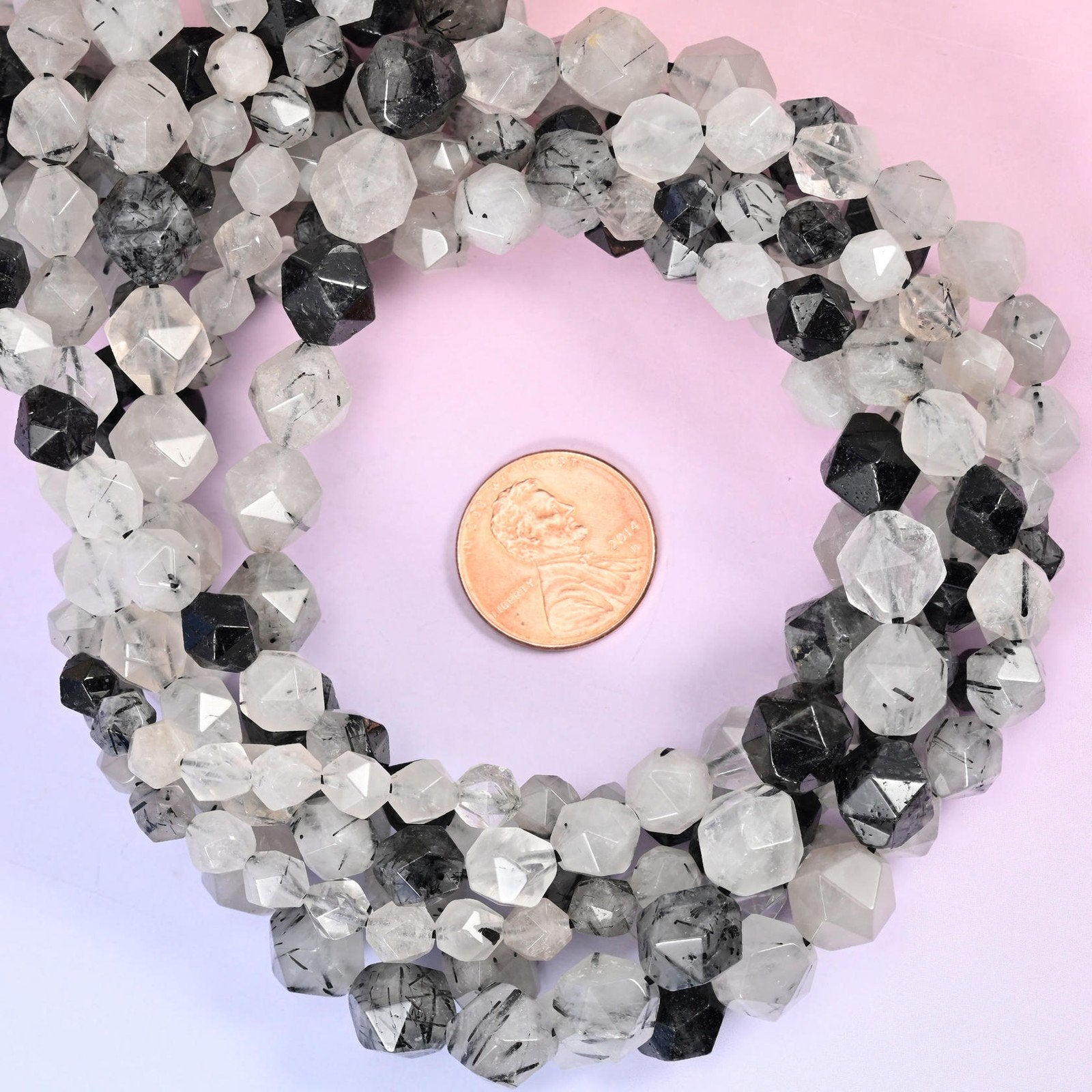 Black Rutilated Quartz faceted diamond star cut bead strands coiled around a US penny for size reference