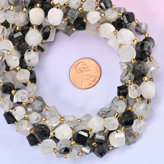 Black Rutilated Quartz faceted spiral twist bead strands coiled around a US penny for size reference