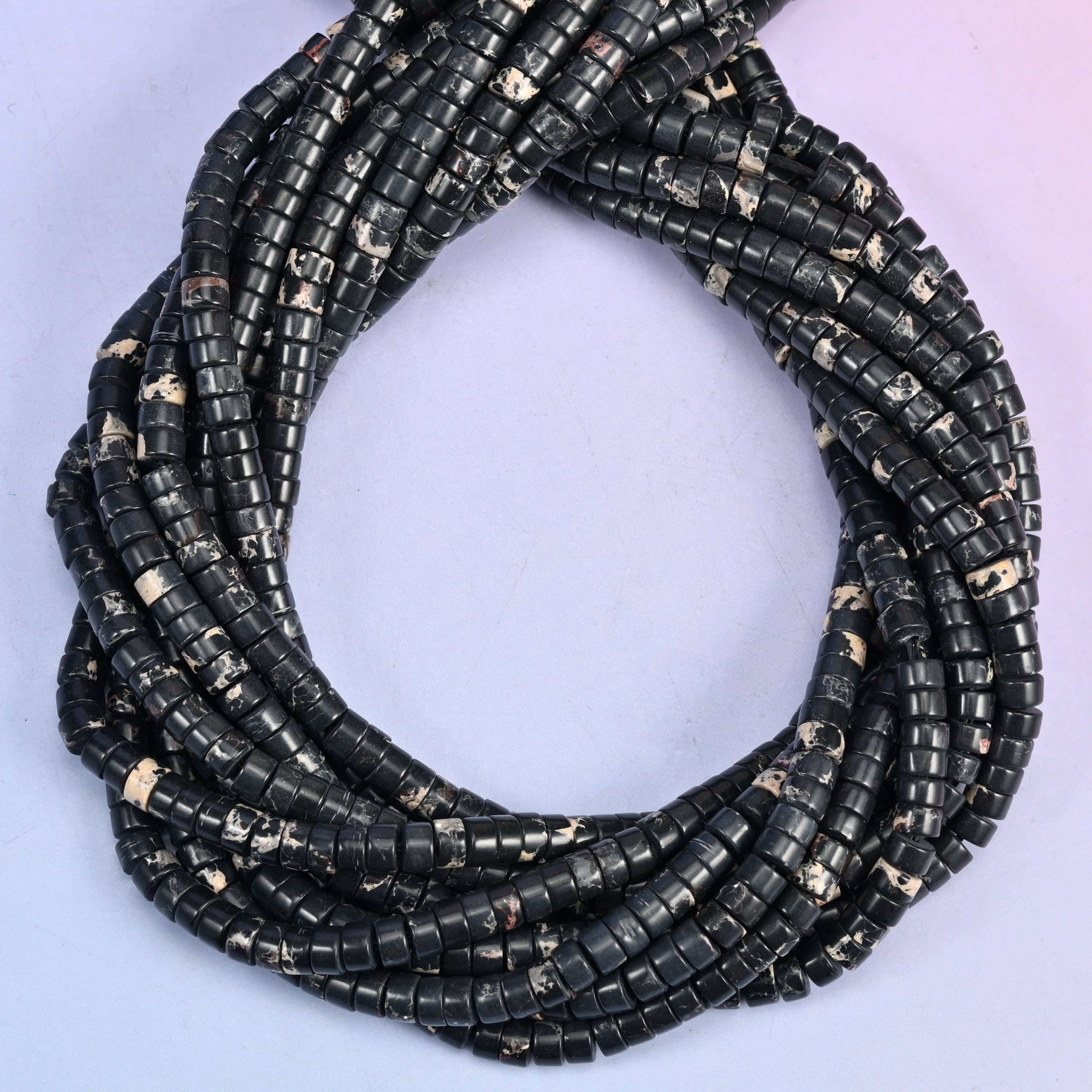 Black Sea Sediment Jasper smooth heishi disc beads, close view of the coiled strands showing black with cream and gold flecks