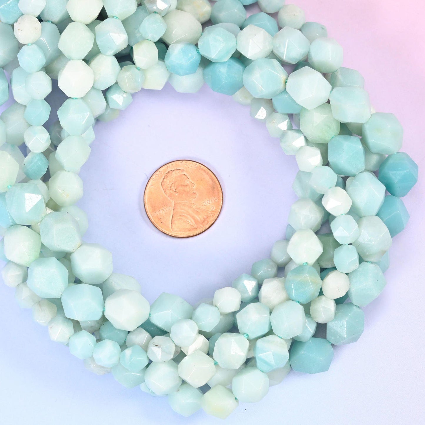 Blue Amazonite faceted diamond star cut bead strands coiled around a US penny for size reference