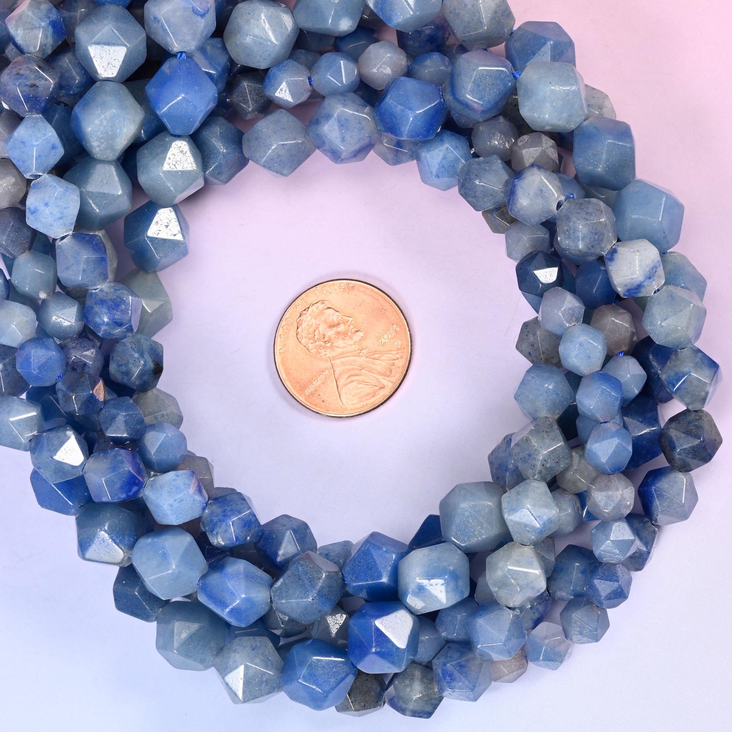 Blue aventurine faceted diamond star cut bead strands coiled around a US penny for size reference
