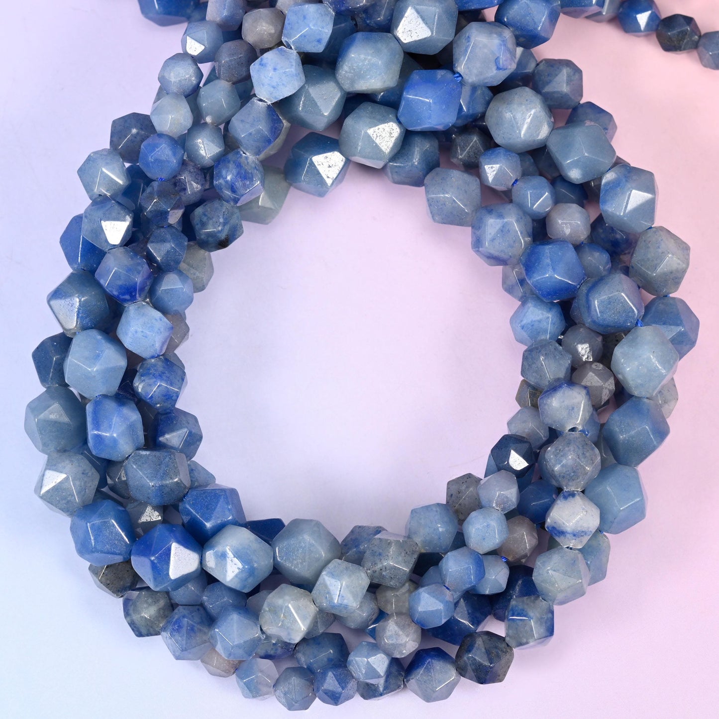 Blue aventurine faceted diamond star cut beads, strands coiled into a ring showing the denim blue stone and its cut facets