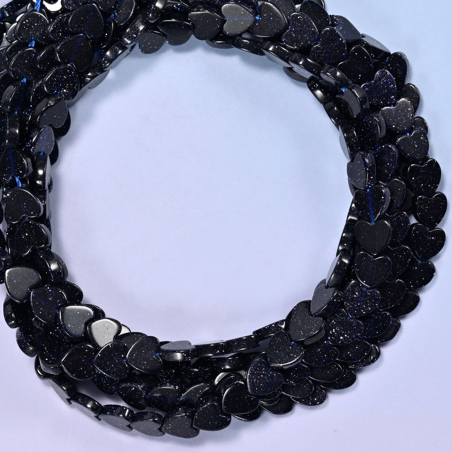 Blue Sandstone flat heart beads, close view of the coiled strands in near-black navy flecked with glitter
