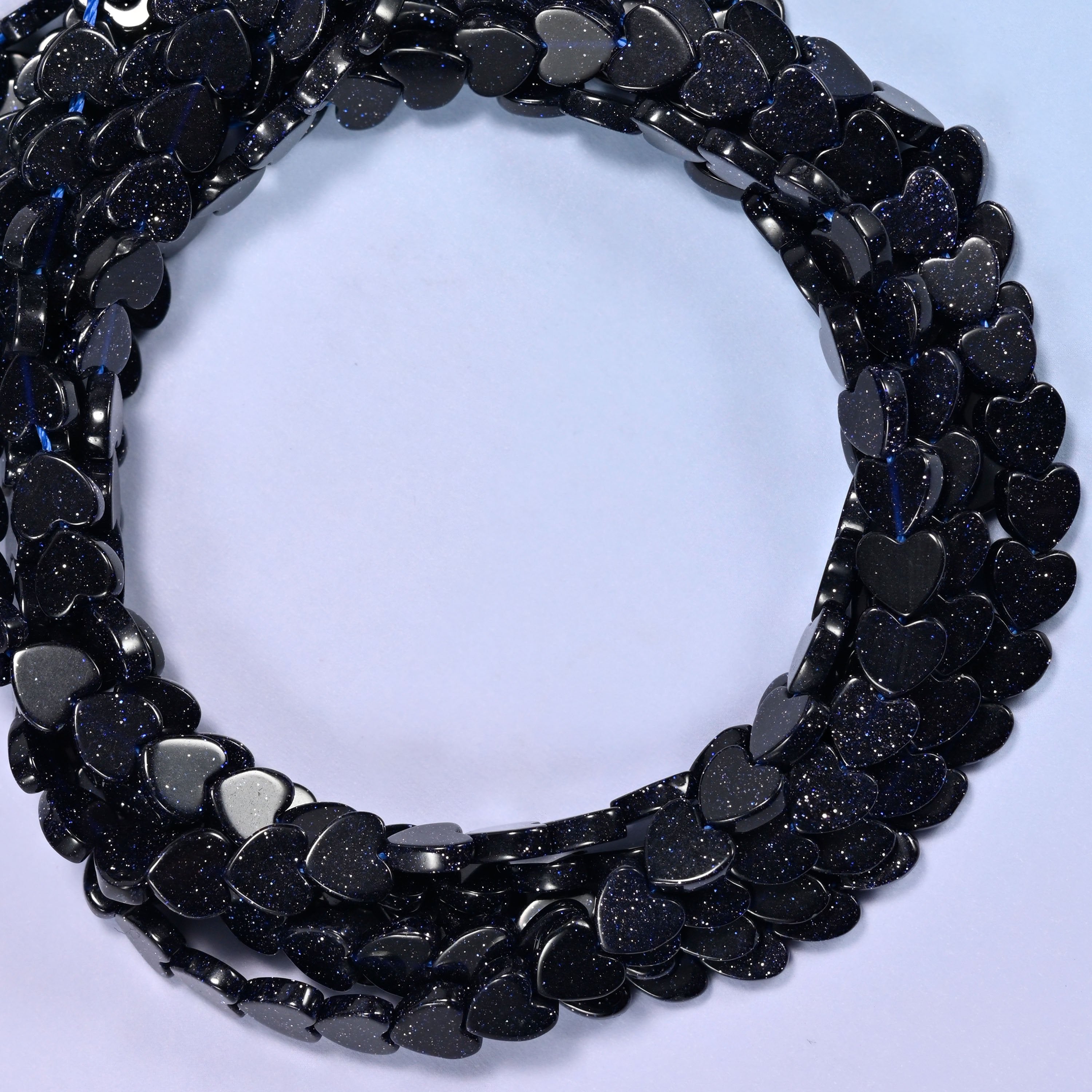 Blue Sandstone flat heart beads, close view of the coiled strands in near-black navy flecked with glitter