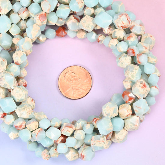Blue Shoushan stone faceted diamond star cut bead strands coiled around a US penny for size reference