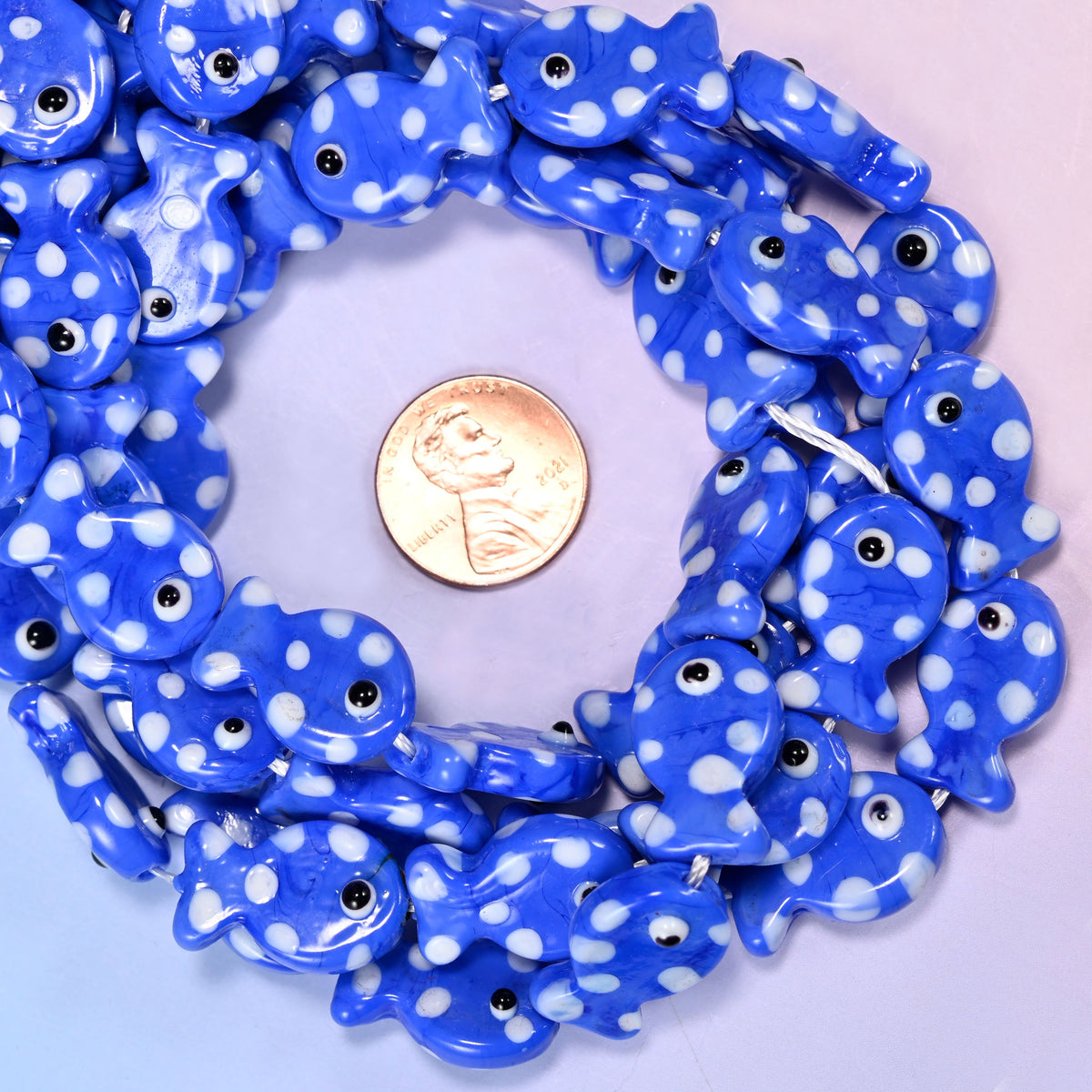 Blue with White Dot Fish glass bead strands coiled around a US penny for size reference