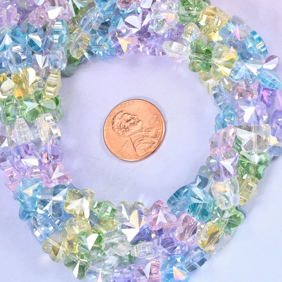 Transparent butterfly glass bead strands coiled around a US penny for size reference