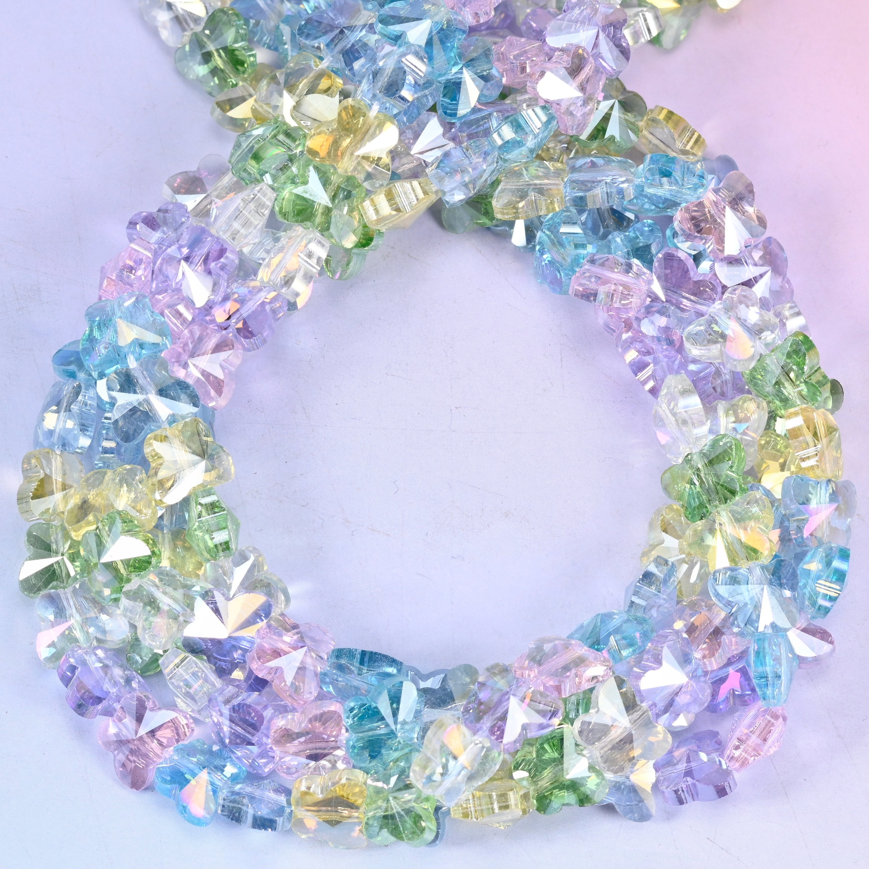 Transparent butterfly glass beads, close view of the coiled strands mixing clear pastel blue, green, lilac and pink
