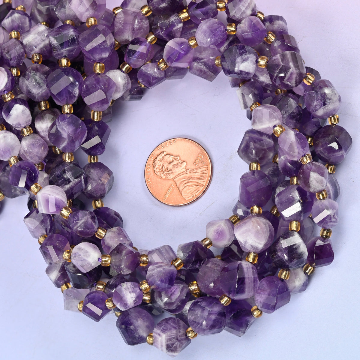 Chevron Amethyst faceted spiral twist bead strands coiled around a US penny for size reference
