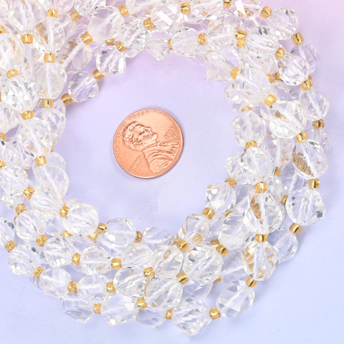Clear Quartz faceted spiral twist bead strands coiled around a US penny for size reference