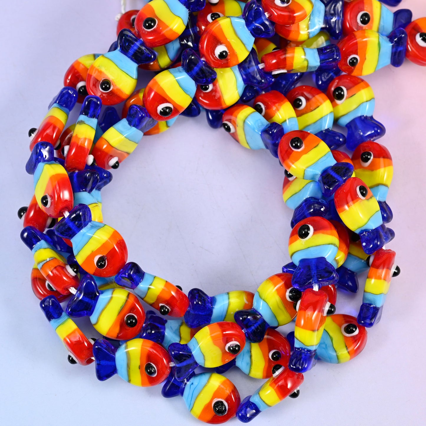 Colorful Fish glass beads, close view of the coiled strands striped in red, orange, yellow and blue