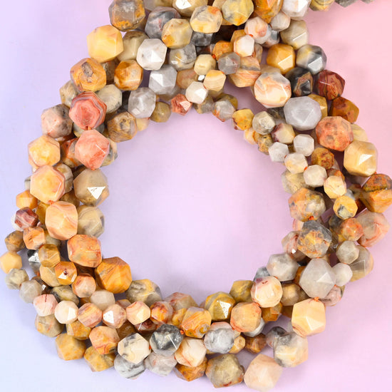 Crazy agate faceted diamond star cut beads, strands coiled into a ring showing the cream, apricot and grey swirling