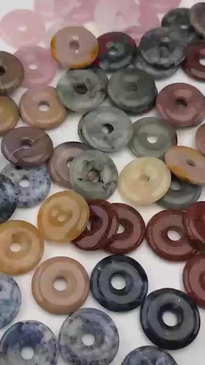 Polished 30mm crystal donut pendants in mixed stones, shown loose in a pile