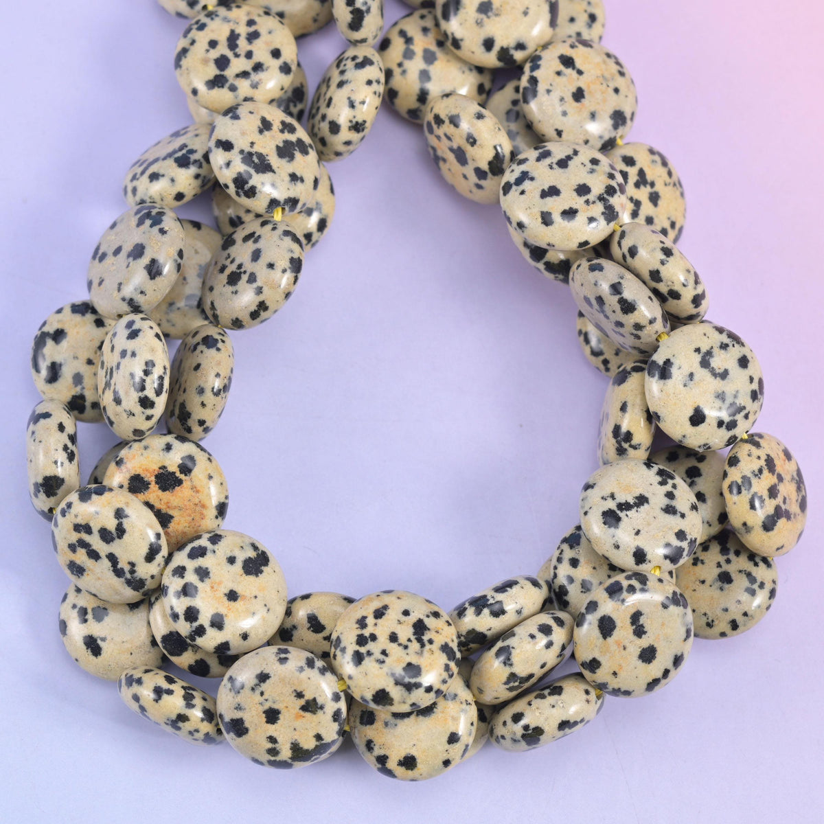 Dalmatian Jasper smooth coin beads, close view of the coiled strands showing cream with black spotting