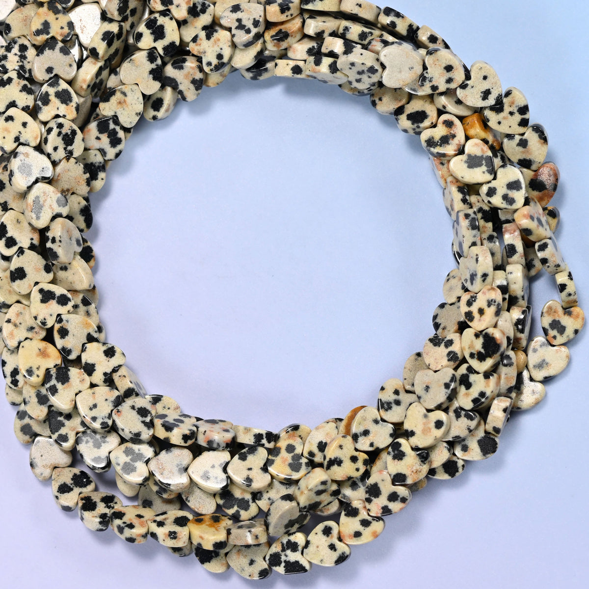 Dalmatian Jasper flat heart beads, close view of the coiled strands in cream with black spotting