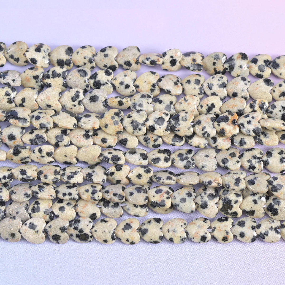 Dalmatian jasper heart beads, close view of several strands showing the puffed heart shape.