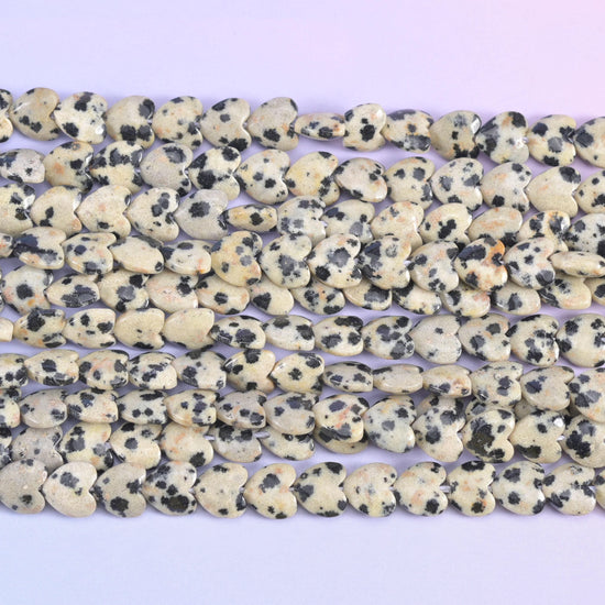 Dalmatian jasper heart beads, close view of several strands showing the puffed heart shape.