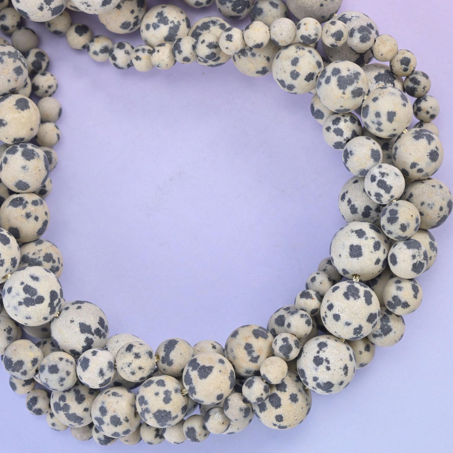 Dalmatian Jasper matte round beads, close view of the coiled strands showing cream with black spotting