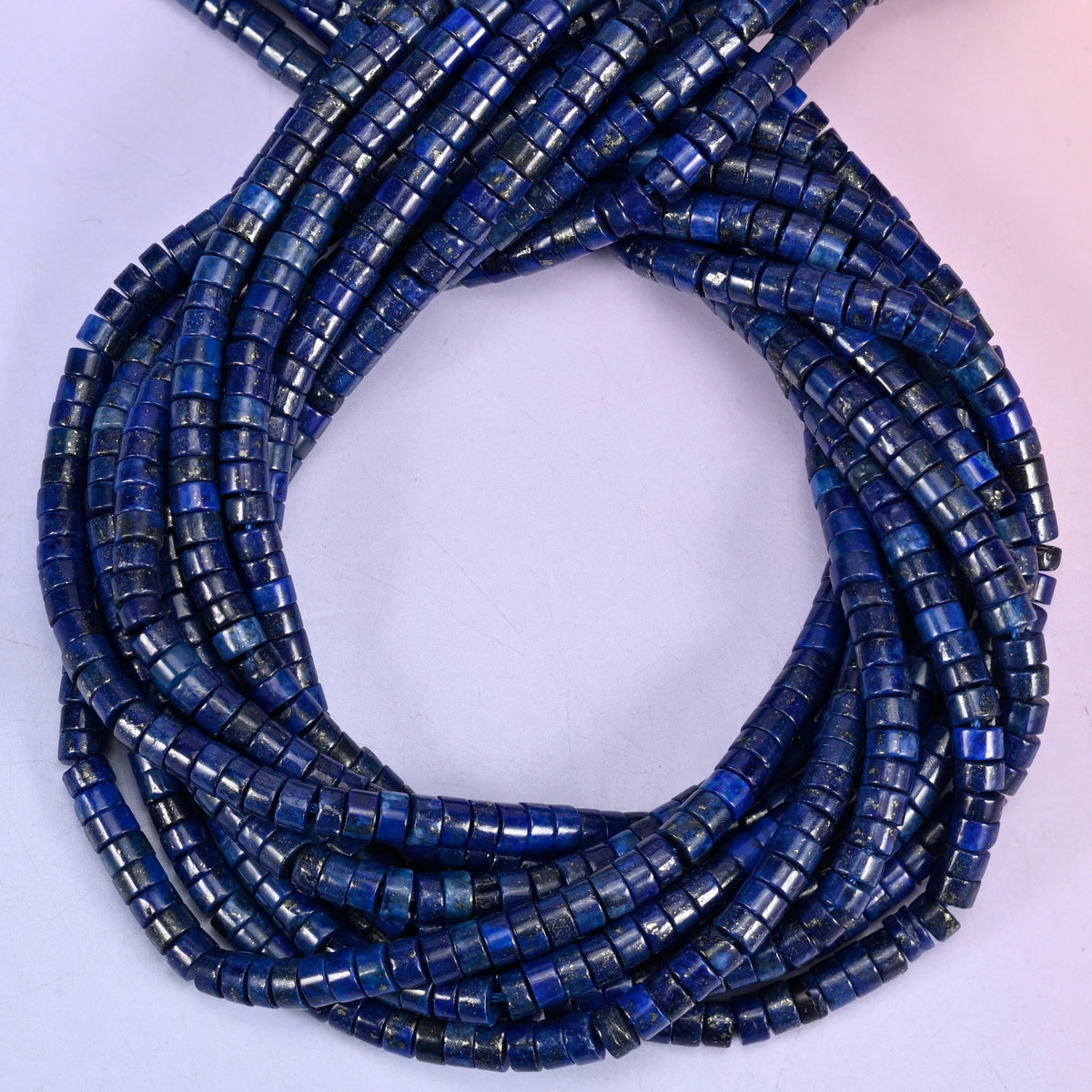Dark Blue Lapis smooth heishi disc beads, close view of the coiled strands showing deep navy blue with grey and gold flecks