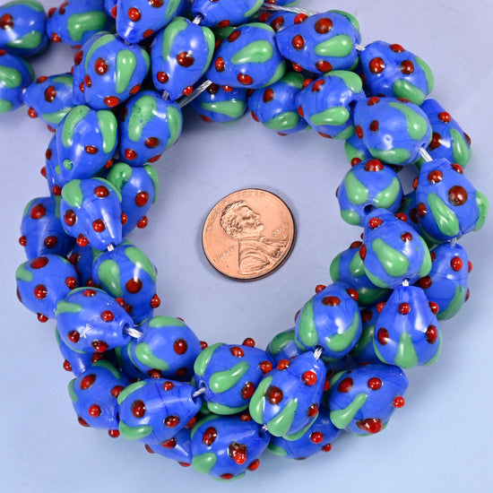 Dark Blue Red Dots Strawberry glass bead strands coiled around a US penny for size reference