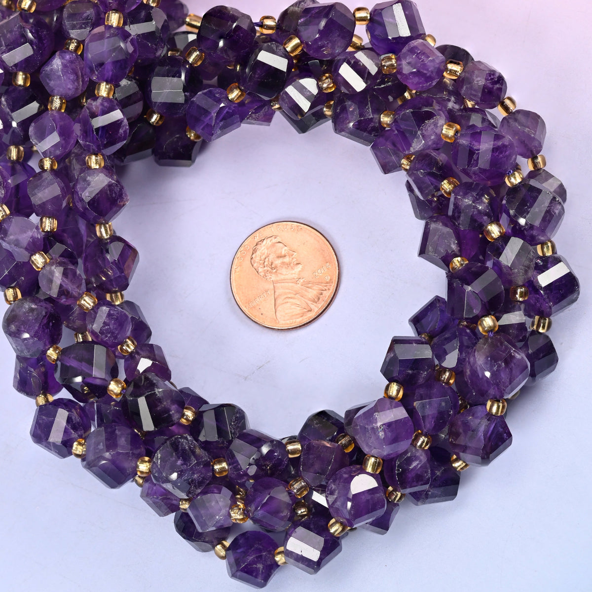 Dark Purple Amethyst faceted spiral twist bead strands coiled around a US penny for size reference