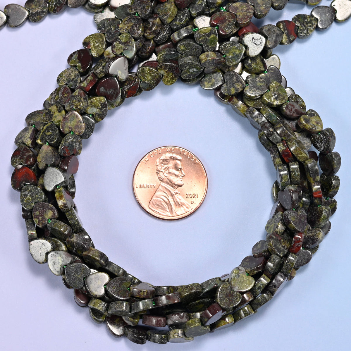 Dragon Bloodstone flat heart bead strands coiled around a US penny for size reference