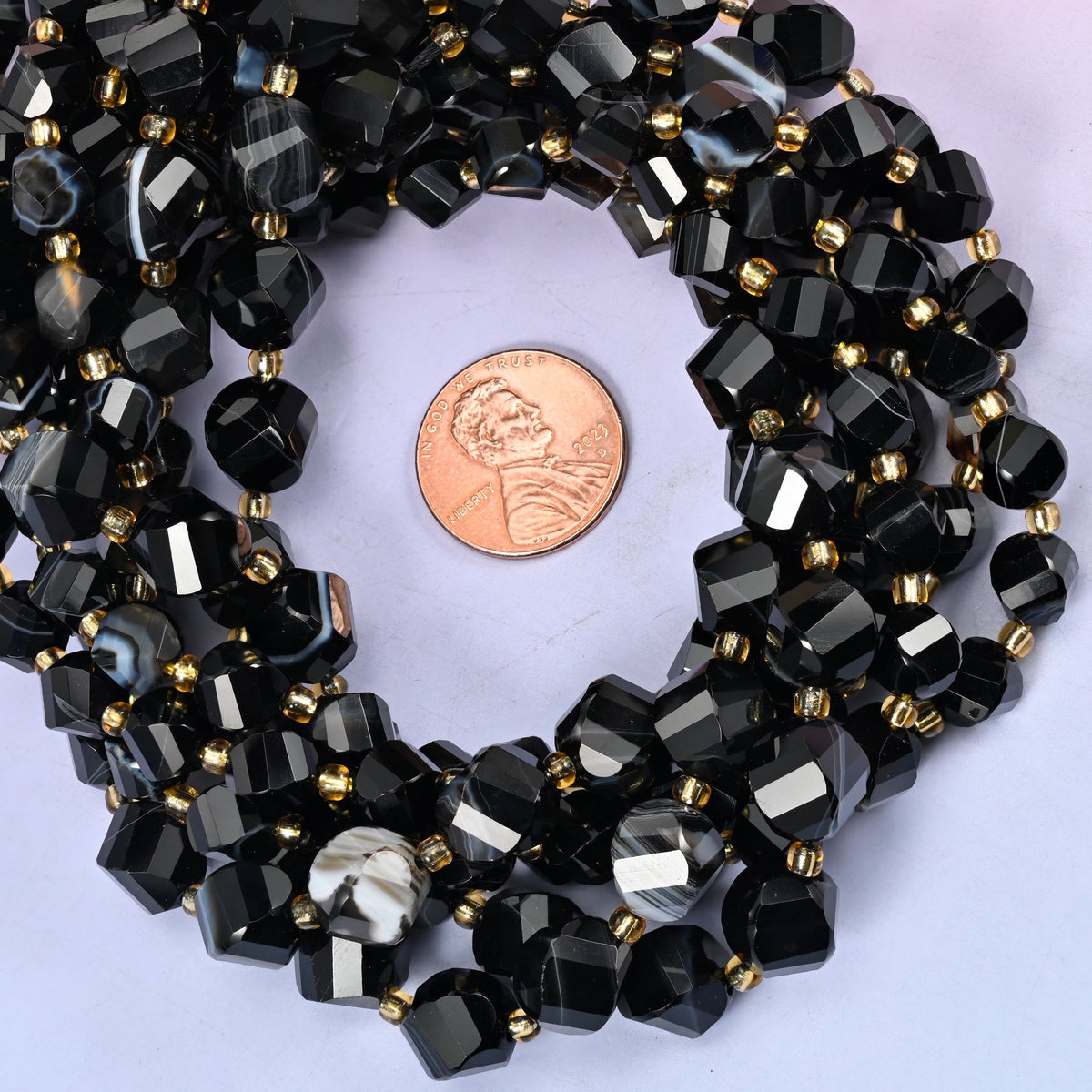 Dyed Black Strip Agate faceted spiral twist bead strands coiled around a US penny for size reference