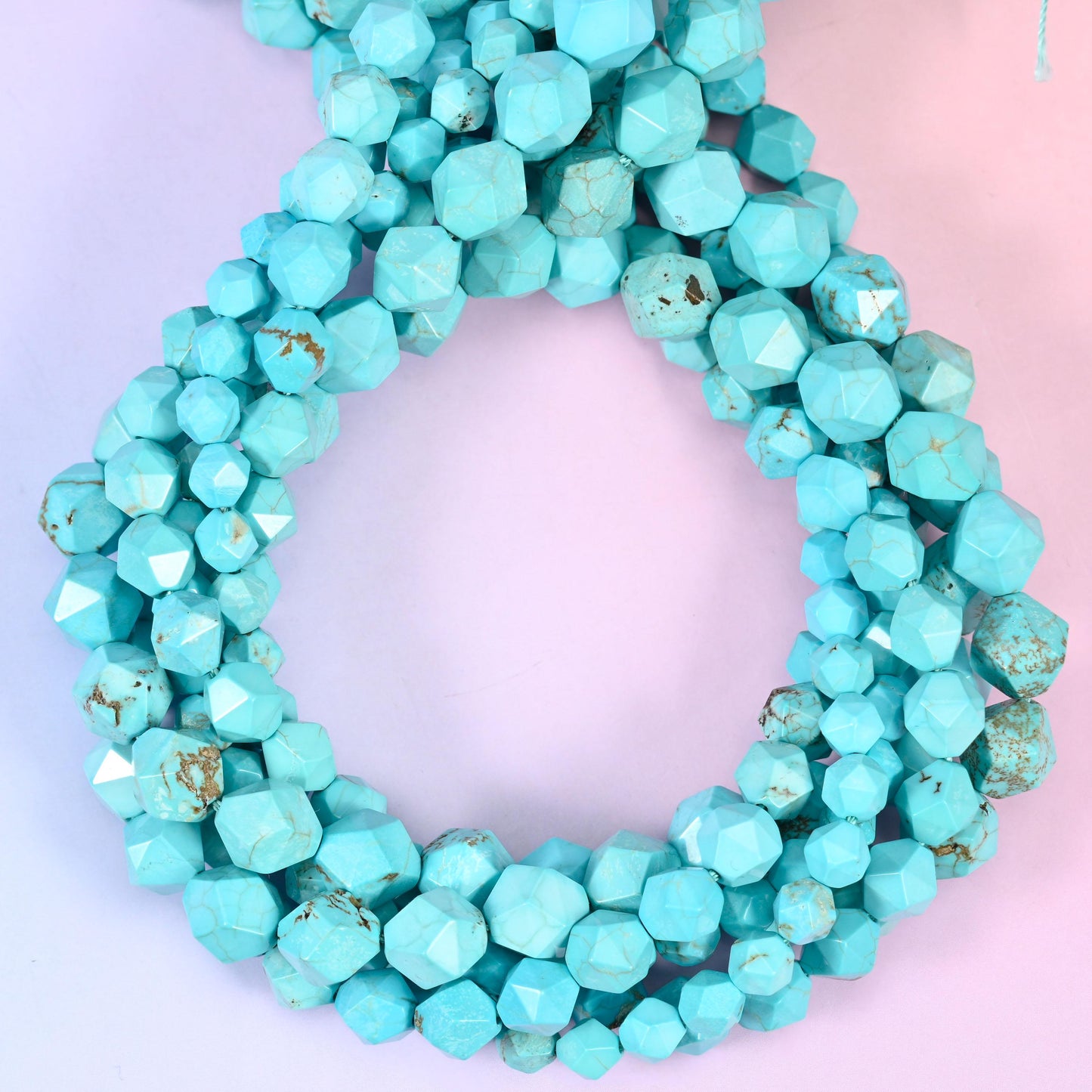 Dyed blue howlite faceted diamond star cut beads, strands coiled into a ring showing the even turquoise colour and fine grey veining