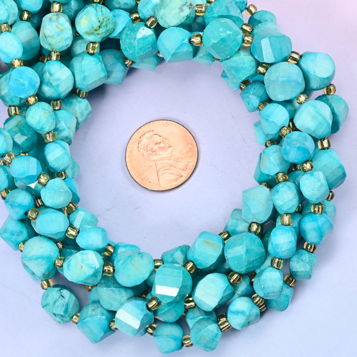 Dyed Lake Blue Howlite faceted spiral twist bead strands coiled around a US penny for size reference