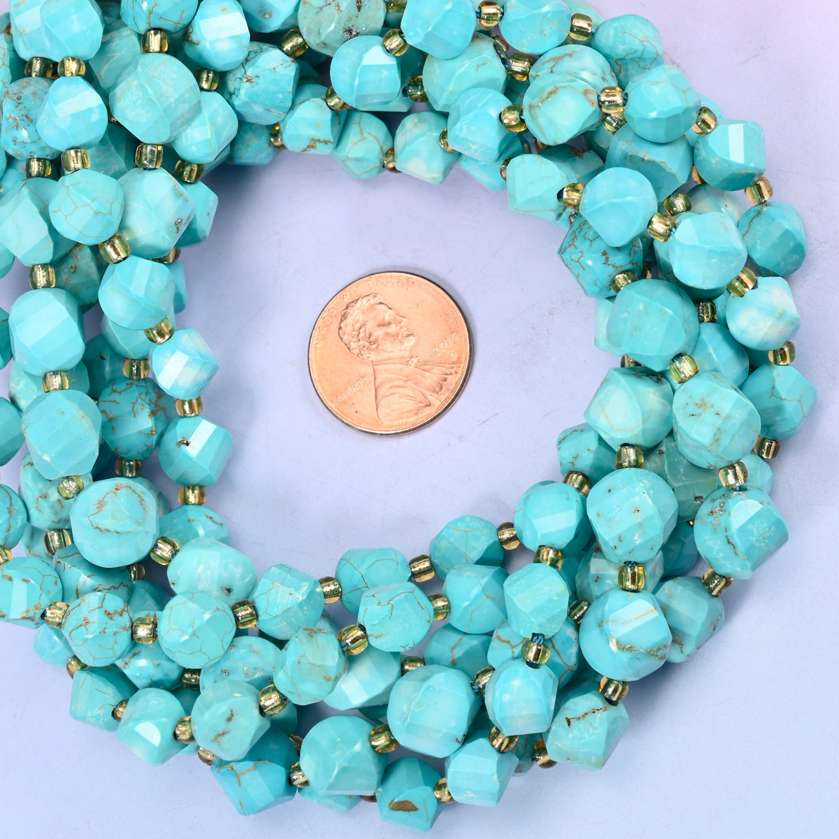 Dyed Light Blue Howlite faceted spiral twist bead strands coiled around a US penny for size reference