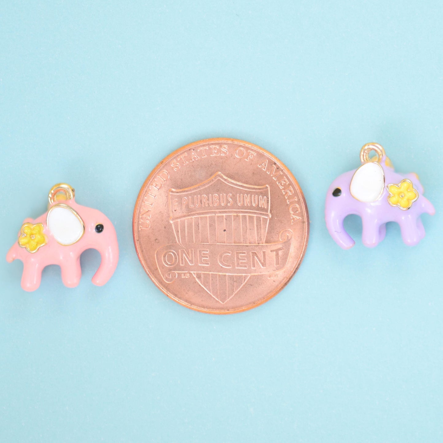 Pink and lilac enamel elephant charms shown either side of a US penny for size reference