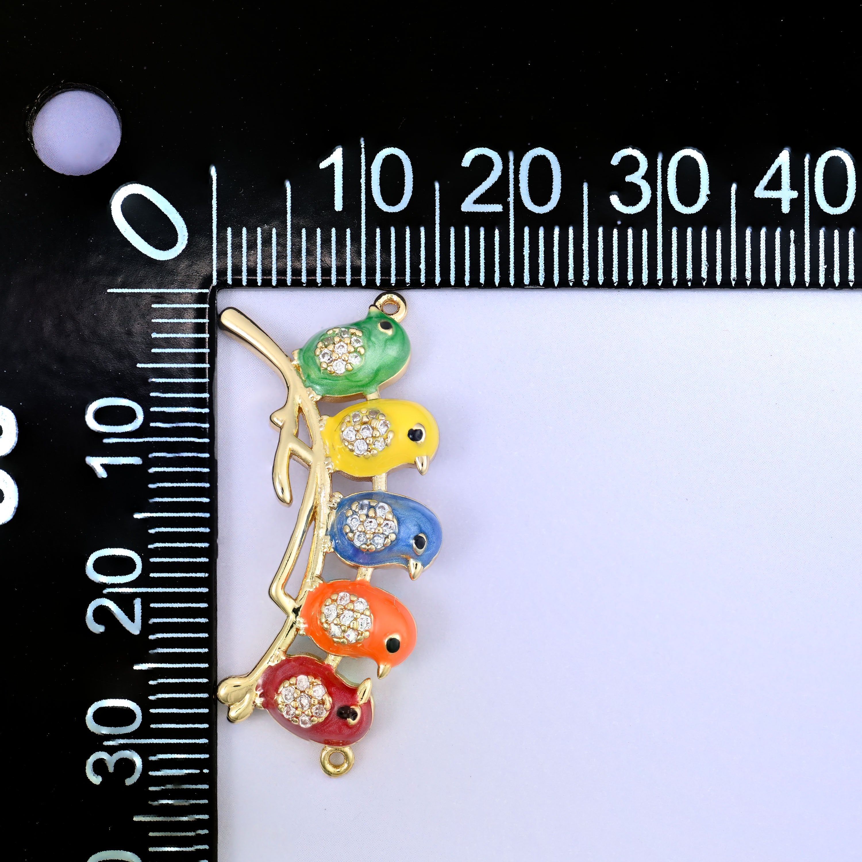 Five enamel birds on a gold branch connector, shown vertically beside a millimetre ruler for scale