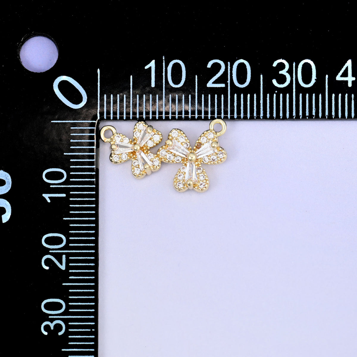 A flower zircon connector pendant photographed beside a millimetre ruler for scale