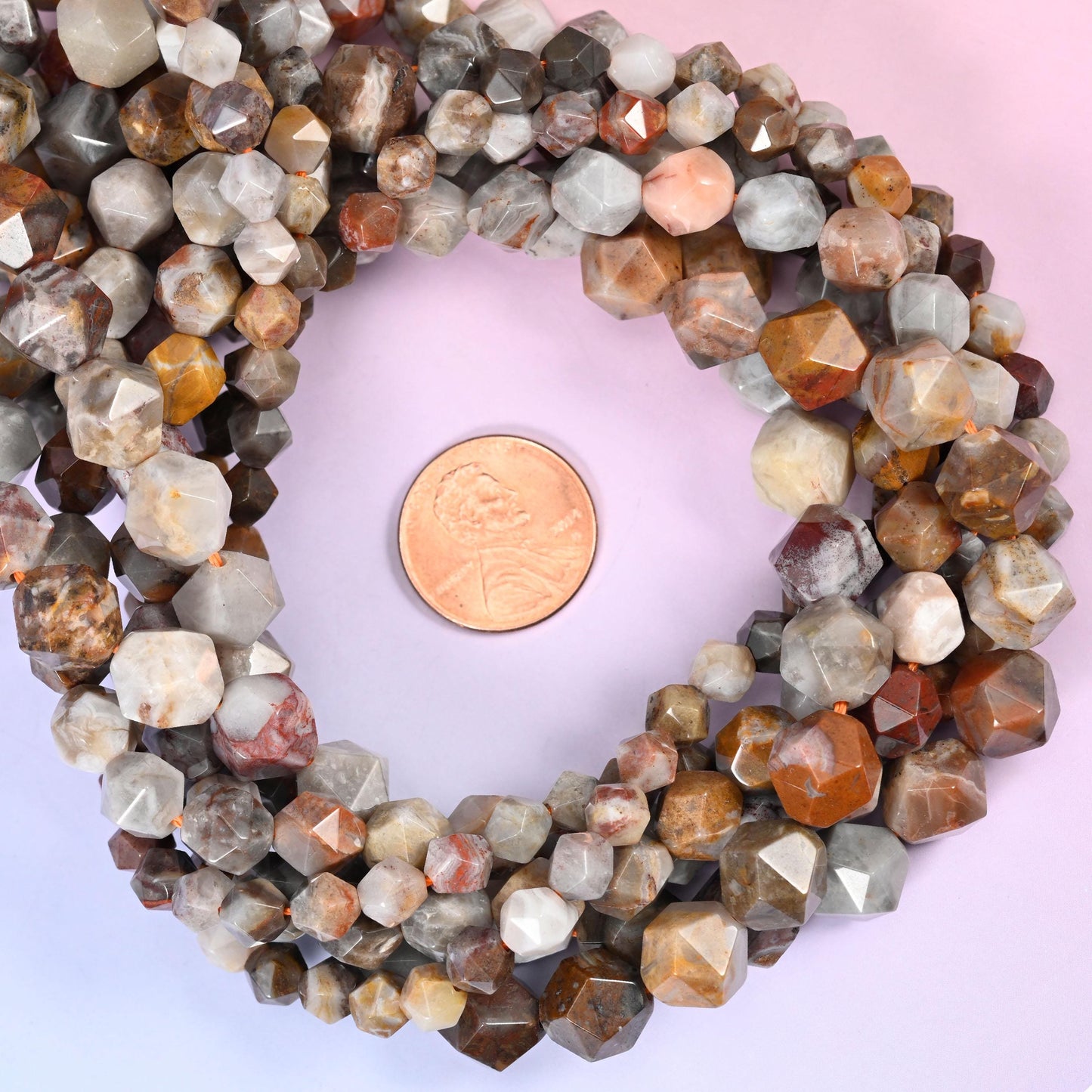 Gobi desert agate faceted diamond star cut bead strands coiled around a US penny for size reference